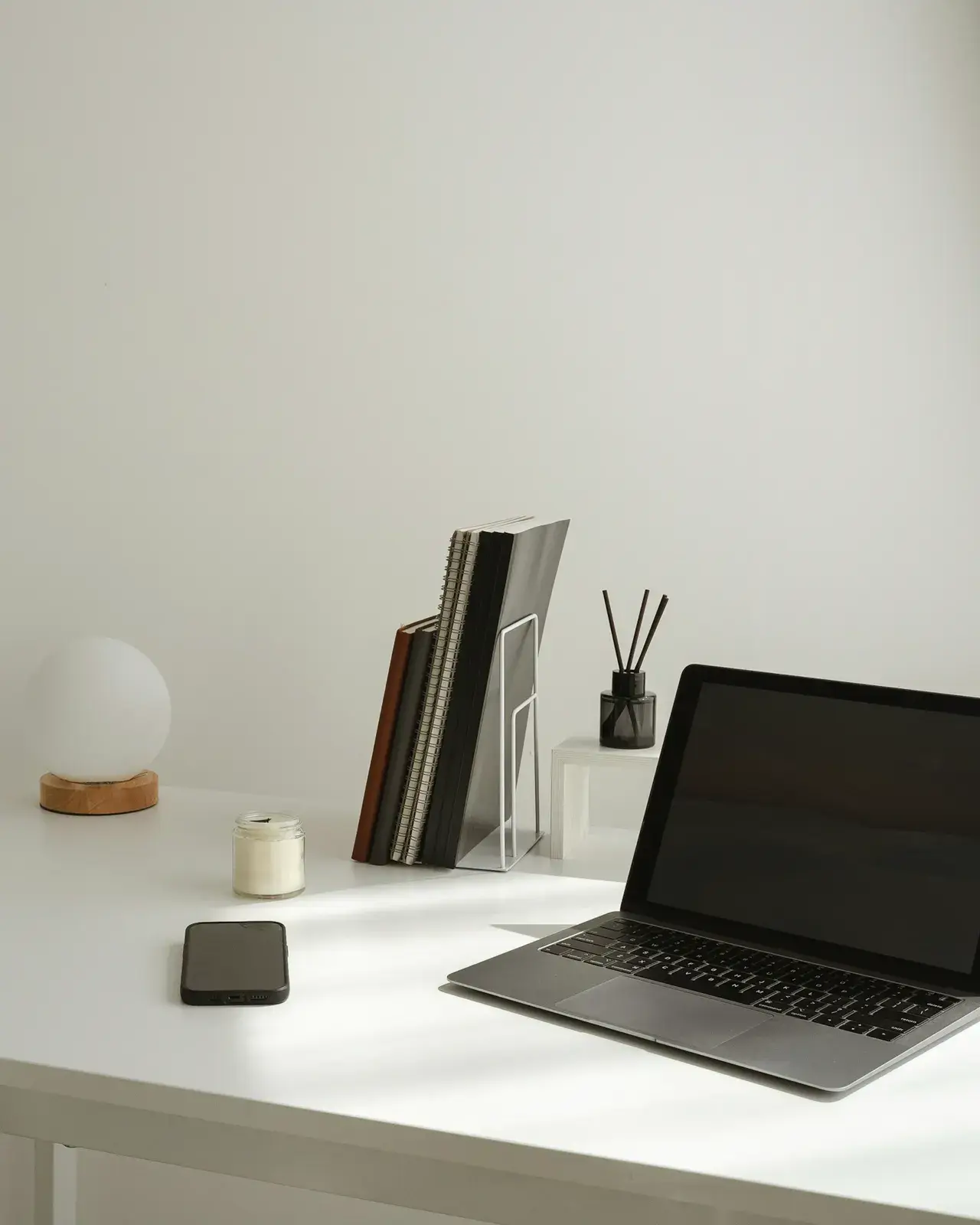 A calm, minimal desk with a laptop, notebooks, and no clutter