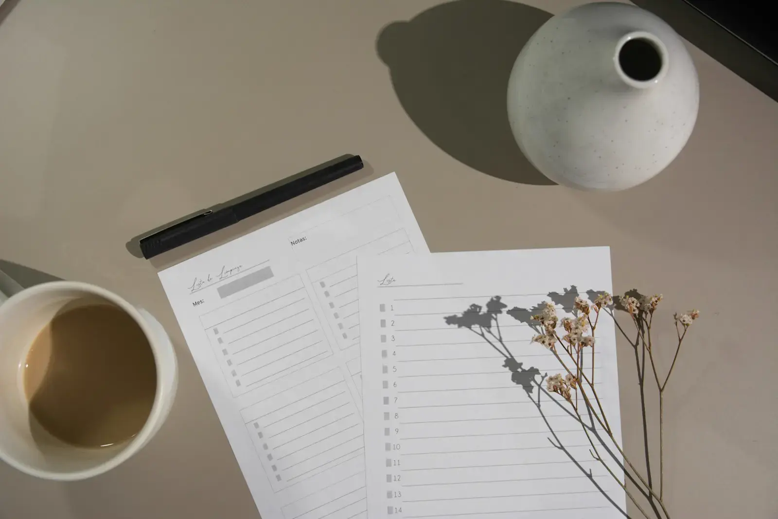 Printed checklist sheets and a pen on a desk beside a cup of coffee