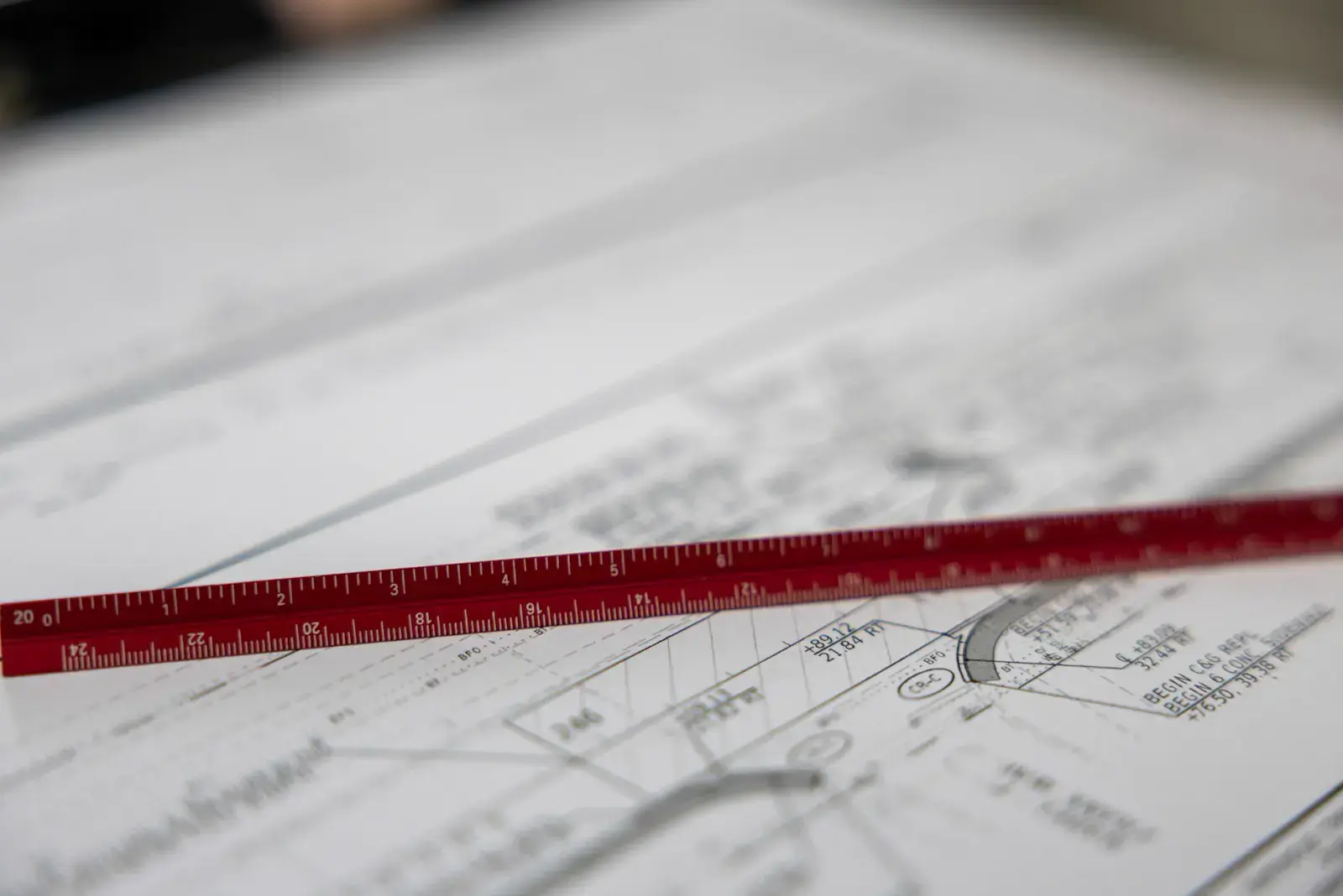 A red scale ruler lying across printed construction drawings