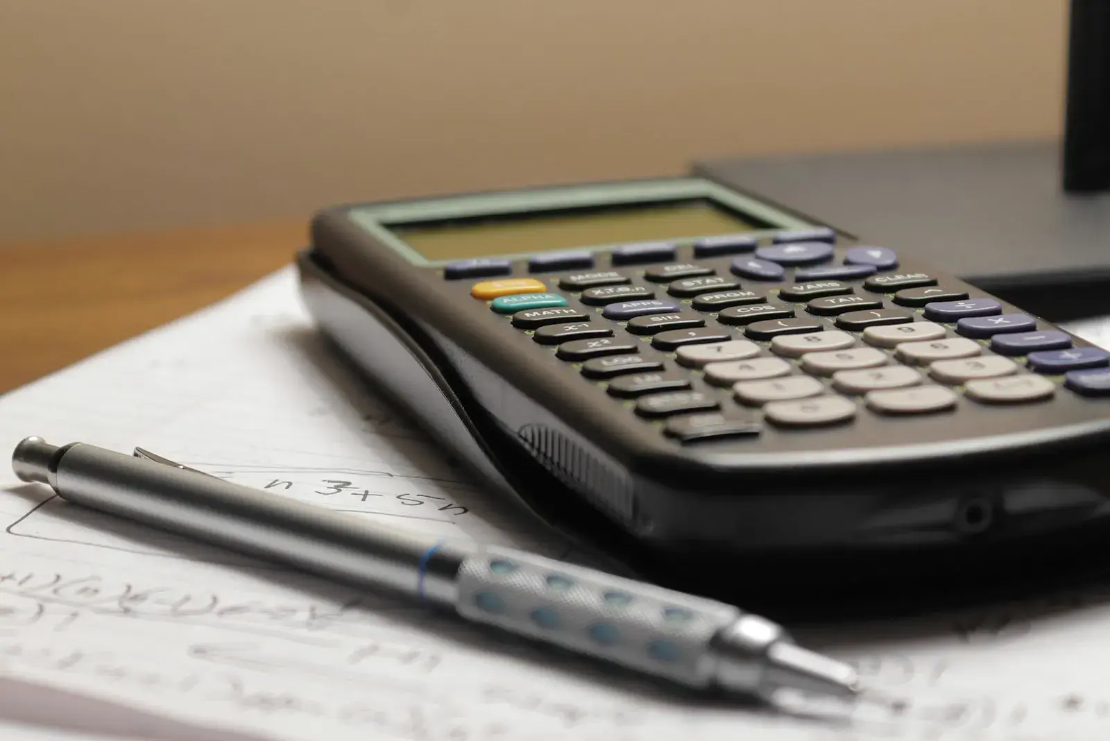 A calculator and mechanical pencil on a page of handwritten figures