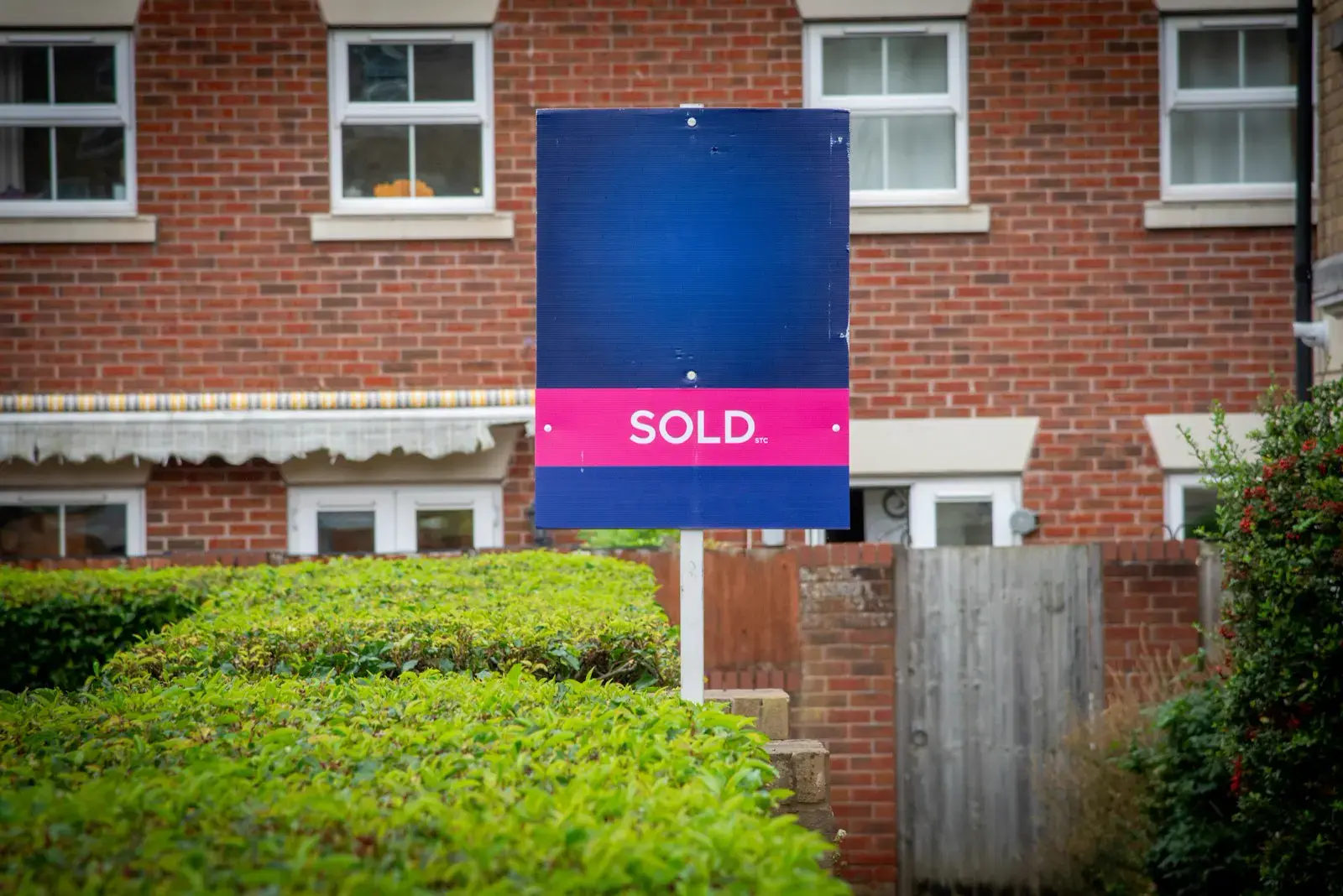 A sold sign in front of a row of brick townhouses