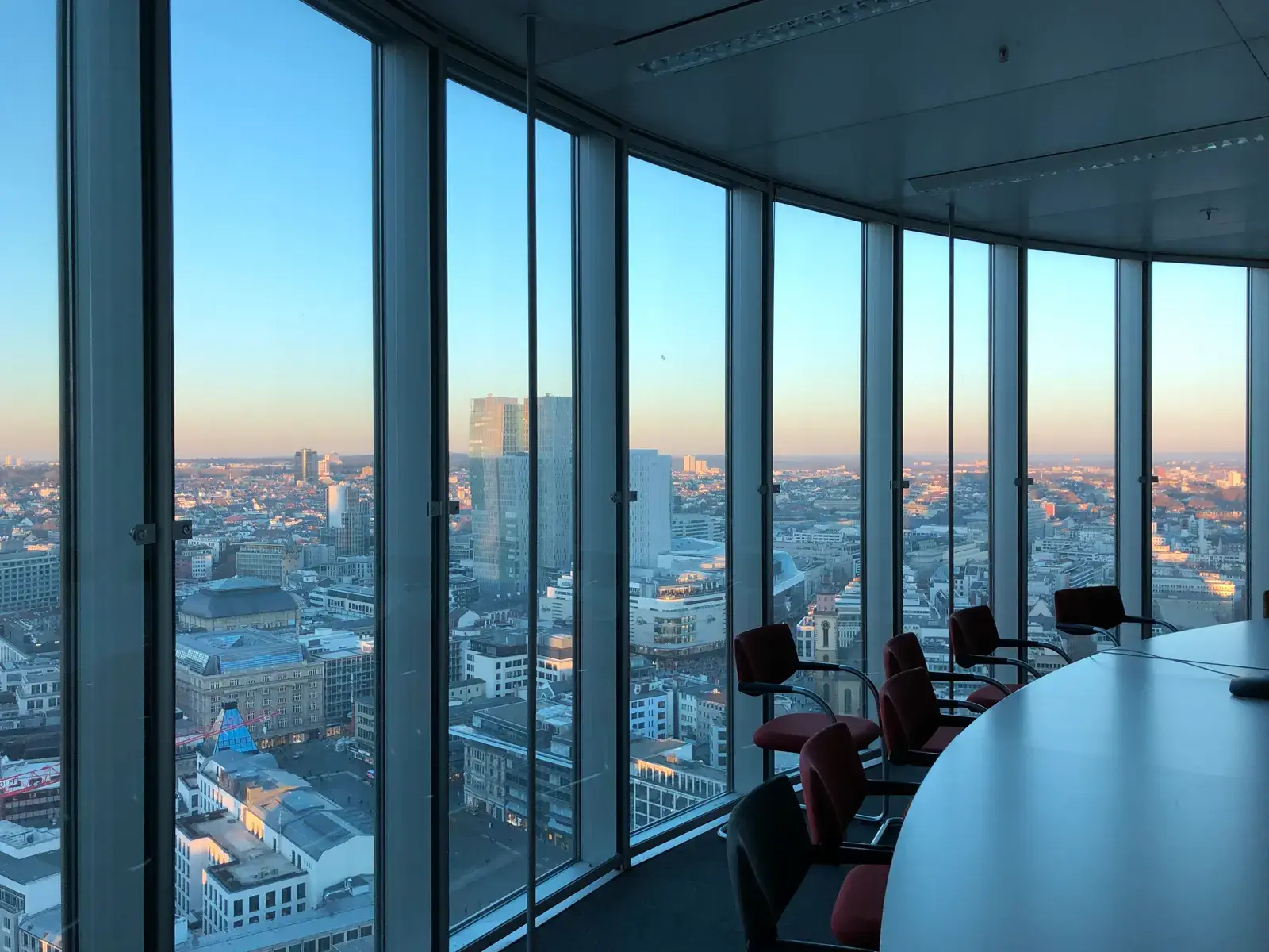 An empty boardroom with a conference table overlooking a city skyline