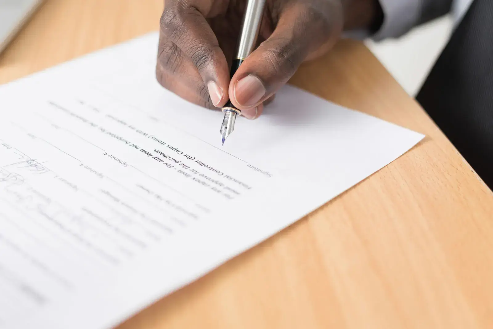 A hand signing a legal document with a fountain pen